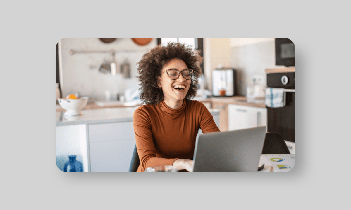 Woman laughing looking at a computer screen